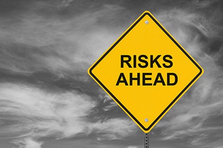 yellow sign that reads risks ahead on it with a stormy background